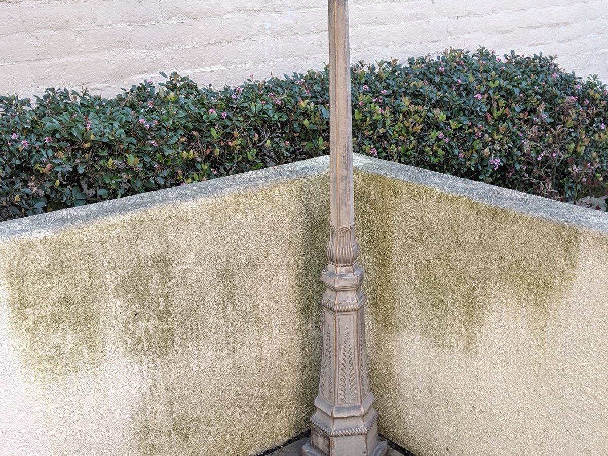 Stucco wall and lamp post with green algae before washing